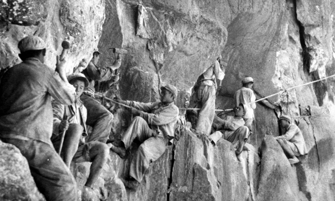 1954年，修筑康藏公路的解放軍戰(zhàn)士們?cè)谂瓋砂兜膽已露副谏媳偕街?。新華社稿 李萬(wàn)春、張加里攝